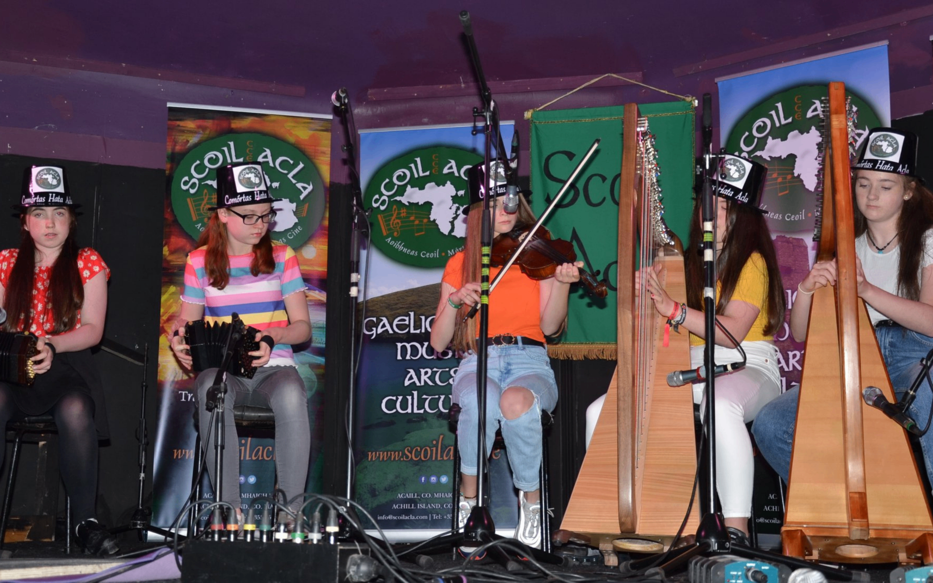 Young musicians performing at Comórtas Hata Acla wearing the traditional top hats